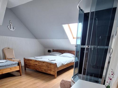 a attic bedroom with a bed and a shower at Agroturystyka nad stawem Mazuchówka in Wydminy