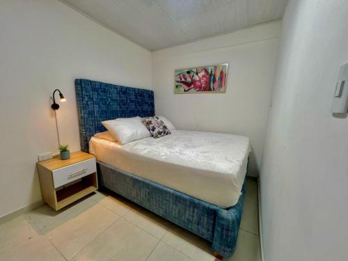 ein kleines Schlafzimmer mit einem Bett mit blauem Kopfteil in der Unterkunft Increible Apto 10Min Base Aérea - Aquaparque Caña in Cali