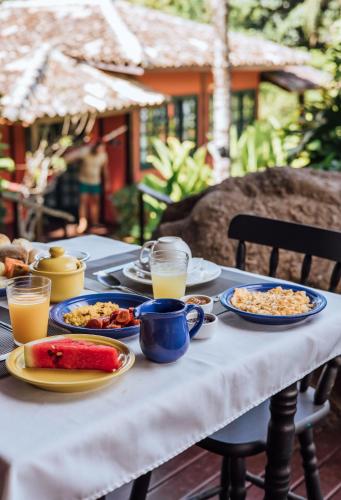 a table with plates of food and glasses of orange juice at Pousada Vila das Pedras in Ilhabela