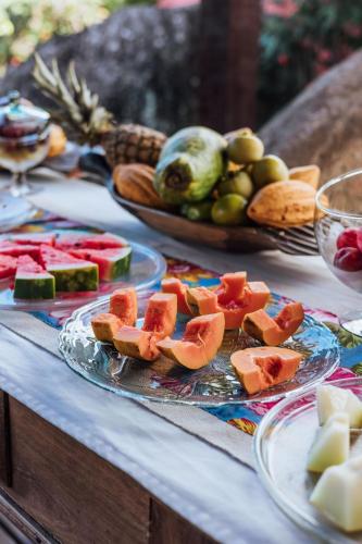 a table topped with plates of fruit on a table at Pousada Vila das Pedras in Ilhabela