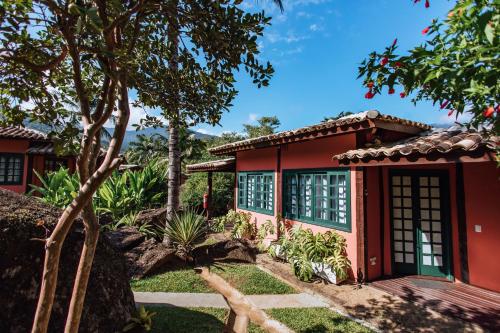 a red house with a tree in front of it at Pousada Vila das Pedras in Ilhabela