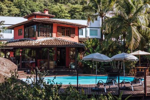 a resort with a swimming pool and a building at Pousada Vila das Pedras in Ilhabela