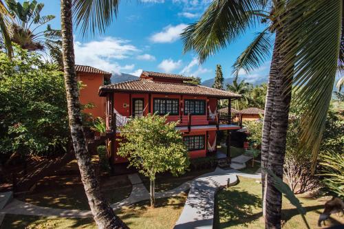 a house with palm trees in front of it at Pousada Vila das Pedras in Ilhabela
