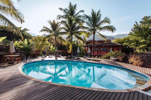 a swimming pool on a wooden deck with palm trees at Pousada Vila das Pedras in Ilhabela