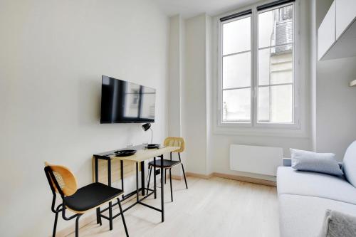 Il comprend un salon blanc doté d'un bureau et d'une télévision. dans l'établissement BUCCI - SAINT GERMAIN Charming apartment, à Paris