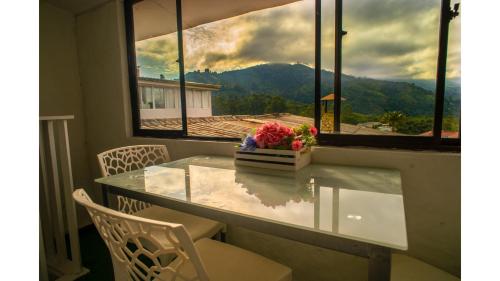 a glass table with chairs and a vase of flowers at Posada del Angel in Salento