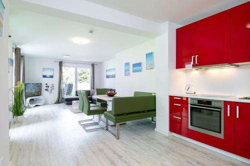 a kitchen with red cabinets and a table with green chairs at Wohnung 2 in Haffkrug