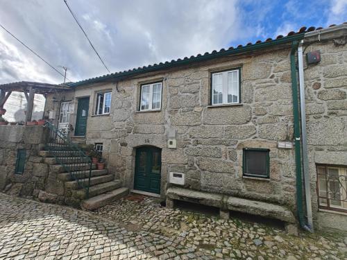 an old stone building with a green door and stairs at Casa Moreirinha in Guarda