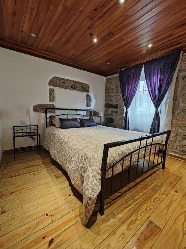 a bedroom with a large bed with purple curtains at Casa Moreirinha in Guarda