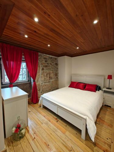 a bedroom with a large white bed with red pillows at Casa Moreirinha in Guarda