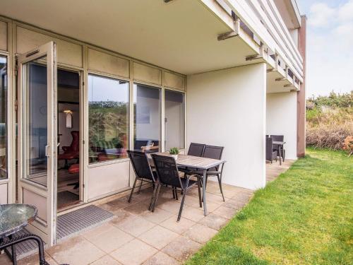 a patio with a table and chairs on the side of a house at 4 person holiday home in Ringkøbing-By Traum in Ringkøbing