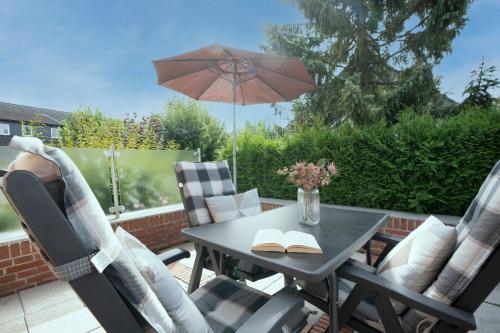 a table and chairs with an umbrella on a patio at Haus Tweeflunken Wohnung 1 in Kellenhusen