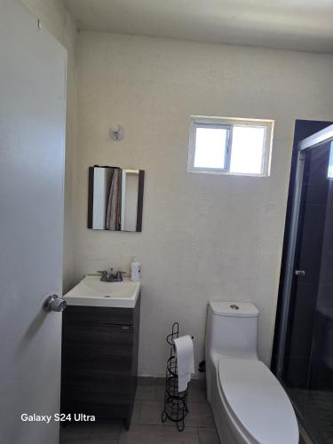 a bathroom with a toilet and a sink and a window at Casa 3 recamaras lavadora secadora NO límite de personas in Hermosillo