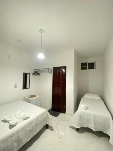 a white room with two beds and a cabinet at Residence Brisa in Jericoacoara