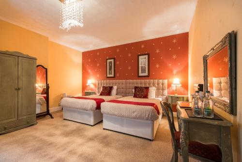 a bedroom with two beds and a mirror at Maenan Abbey Hotel in Llanrwst