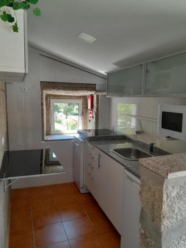 a kitchen with white cabinets and a sink and a window at Casa do Loureiro in Paradela