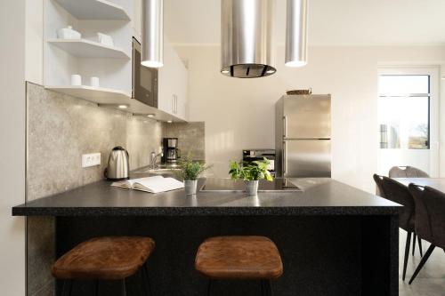 a kitchen with a large black counter with stools at Strandresidenz Vogelflug App 13 in Fehmarnsund