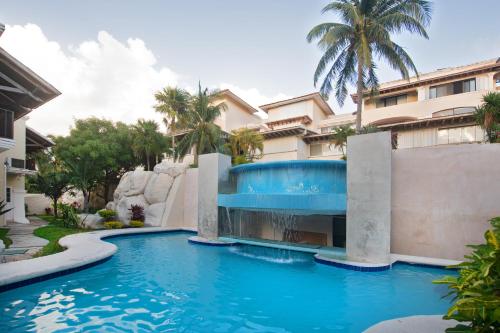 a swimming pool in front of a building with a blue pool at CASCADAS,stylish family villa poolside steps from beach in Cancún