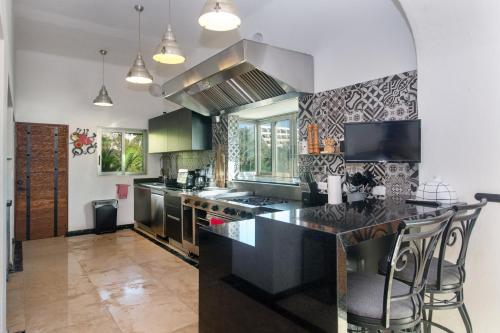 a kitchen with black countertops and a large island at CASCADAS,stylish family villa poolside steps from beach in Cancún