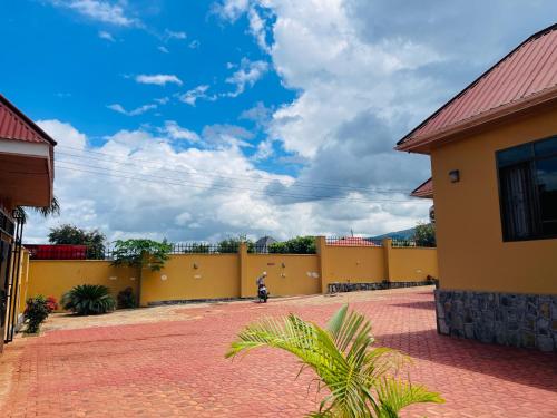 a yellow building with a brick driveway in front of it at KDP LODGE Kihonda in Morogoro