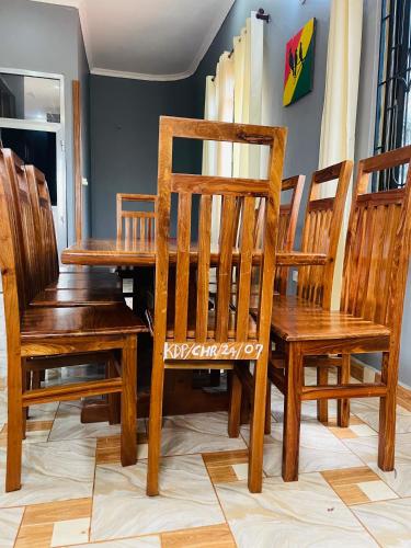 a wooden dining room table with wooden chairs and a wooden table and bench at KDP LODGE Kihonda in Morogoro