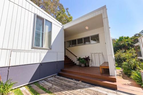 a white house with a wooden porch and a door at The Pavilions at Pearl in Pearl Beach