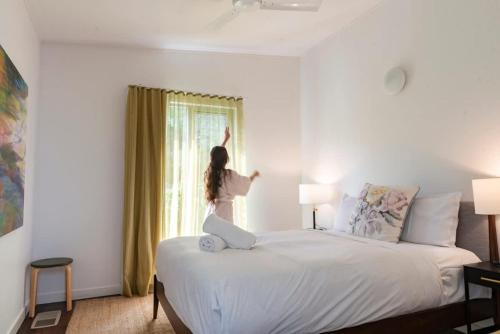a woman sitting on a bed looking out the window at The Pavilions at Pearl in Pearl Beach