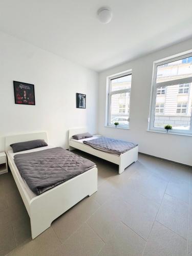 two beds in a white room with two windows at Hollywood Apartment XXL in Bremerhaven