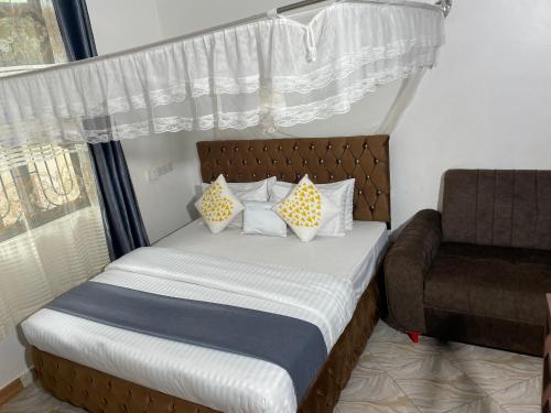 a bedroom with a bed with pillows and a chair at KDP LODGE Kihonda in Morogoro