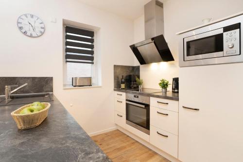 a kitchen with white cabinets and a clock on the wall at Ferienhaus Salomons Sonne in Kellenhusen