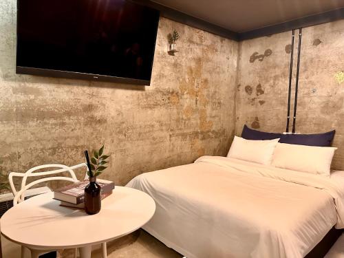 a bedroom with a bed and a table and a tv at Stay Cozy 스테이 하우스 in Ansan