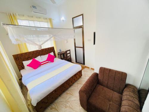 a bedroom with a bed with pink pillows and a chair at KDP LODGE Kihonda in Morogoro