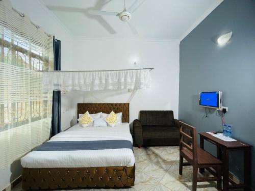 a bedroom with a bed and a chair and a desk at KDP LODGE Kihonda in Morogoro