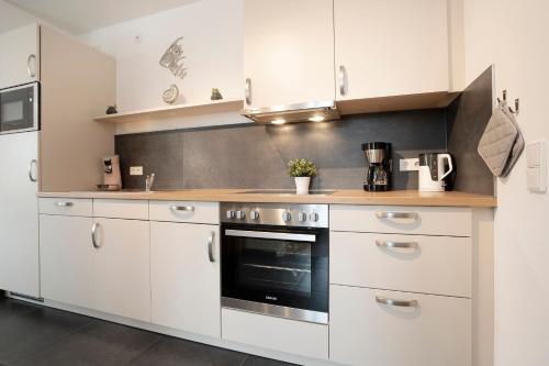 Una cocina con gabinetes blancos y una estufa. en KellenHus Wohnung 7, en Kellenhusen