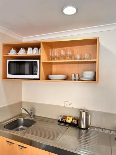 a kitchen with a sink and a microwave at Harbour City Motor Inn & Conference in Tauranga
