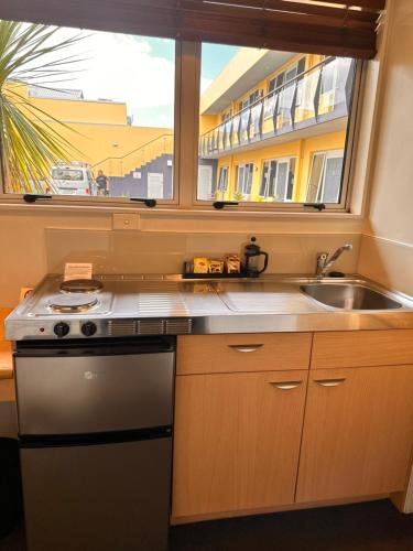 a kitchen with a sink and a window at Harbour City Motor Inn & Conference in Tauranga