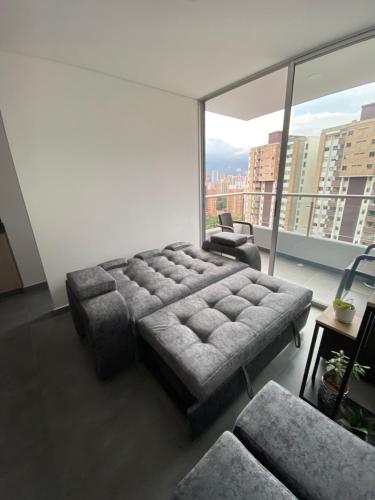 a living room with a couch and a large window at Hermoso y cómodo apartamento in Sabaneta