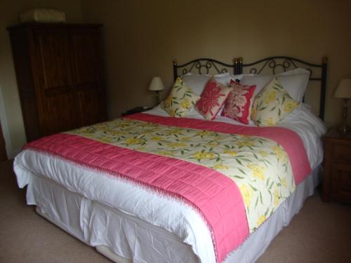 a bed with a pink and white blanket and pillows at The Paddock in Haverfordwest