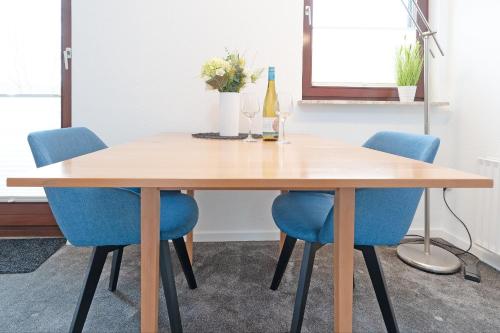 a dining room table with blue chairs and a bottle of wine at Haus Hüttmann Sommerbrise in Gremsmühlen