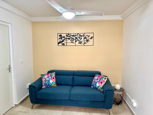 a blue couch in a living room with a ceiling fan at Cocon du Souffleur in Port-Louis