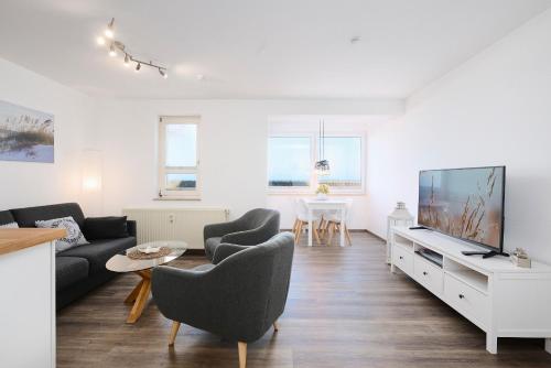 a living room with a couch and a tv at Promenade 27 Koje 23 in Stakendorfer Strand