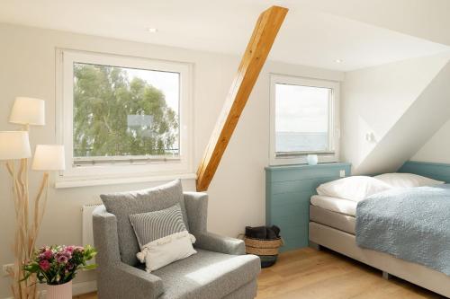 a bedroom with a bed and a chair and a window at Am Strande 31 Nixe in Neustadt in Holstein