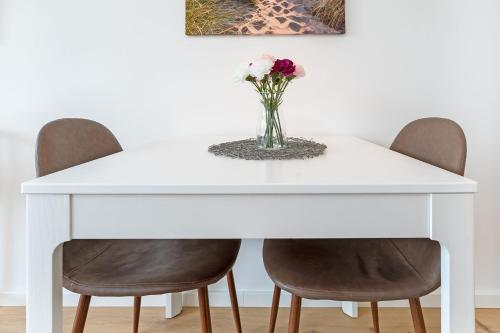 沙博伊茨Haus Meeresstrand BeachBude Scharbeutz的白色的餐桌,配有椅子和花瓶
