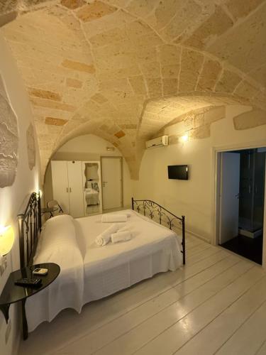 a bedroom with a large white bed with a stone ceiling at Dimora 69 in Lecce