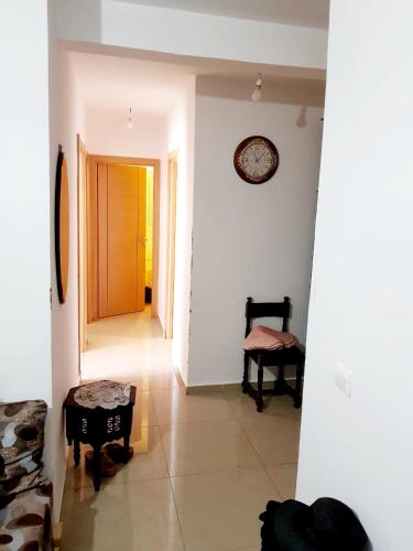 a hallway with a chair and a clock on the wall at Tanger Beach Appartement en Face plage Houara Golf Resort in Dghaliyene