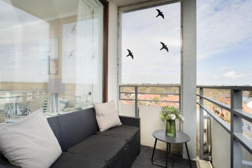 a balcony with a couch and birds in the window at Haus Meeresblick Ankerplatz 84 in Kellenhusen