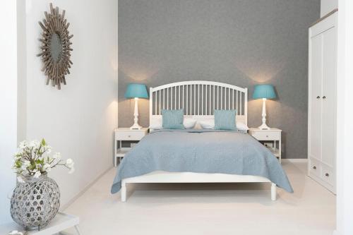 a white bedroom with a bed with blue pillows at Golfplatz Plöner See Großer Plöner See in Bosau