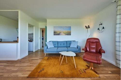 a living room with a blue couch and a red chair at Strandbrise in Fehmarn