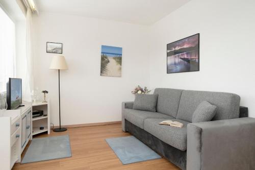 a living room with a gray couch and a tv at Strandhotel Scharbeutz Kleine Krabbe in Scharbeutz