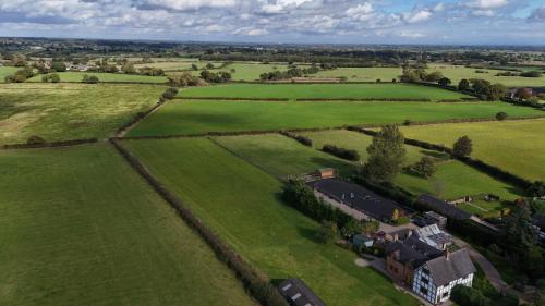 an aerial view of a green field with a house at The Goose lodge in Calveley